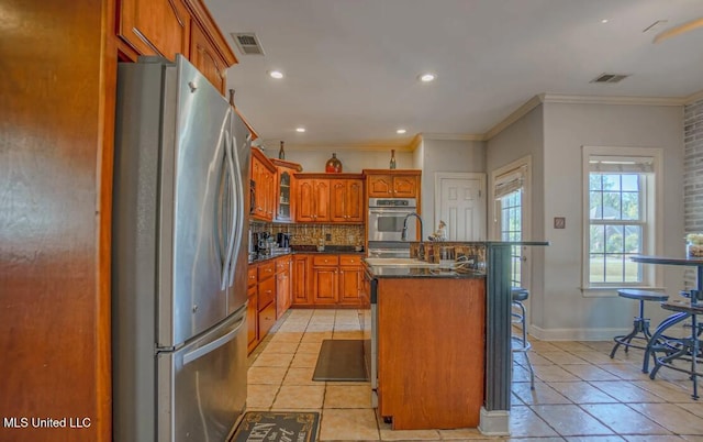 kitchen with stainless steel appliances, an island with sink, light tile patterned floors, tasteful backsplash, and crown molding