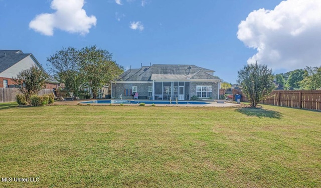 rear view of property featuring a patio, a yard, and a fenced in pool