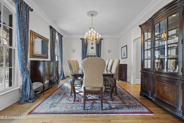 dining area with a notable chandelier, crown molding, and wood-type flooring