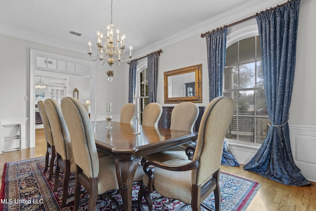 dining room featuring ornamental molding, an inviting chandelier, and light hardwood / wood-style flooring