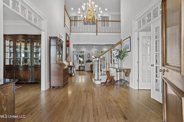 foyer with dark wood-type flooring, ornamental molding, and a high ceiling