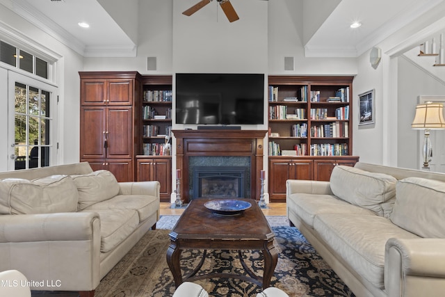 living room featuring crown molding, ceiling fan, a premium fireplace, and hardwood / wood-style floors