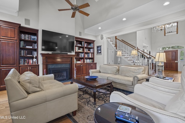 living room featuring ornamental molding, ceiling fan with notable chandelier, high vaulted ceiling, and light hardwood / wood-style flooring