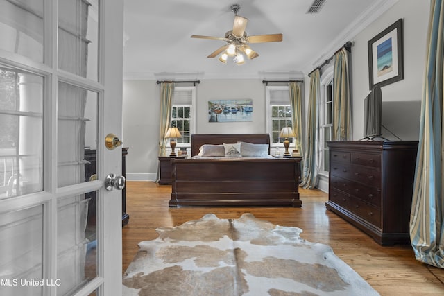 bedroom with crown molding, ceiling fan, multiple windows, and light wood-type flooring