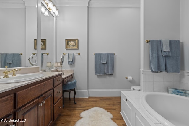 bathroom with toilet, wood-type flooring, ornamental molding, vanity, and a bathing tub