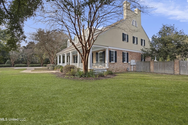 view of side of home featuring a yard and covered porch