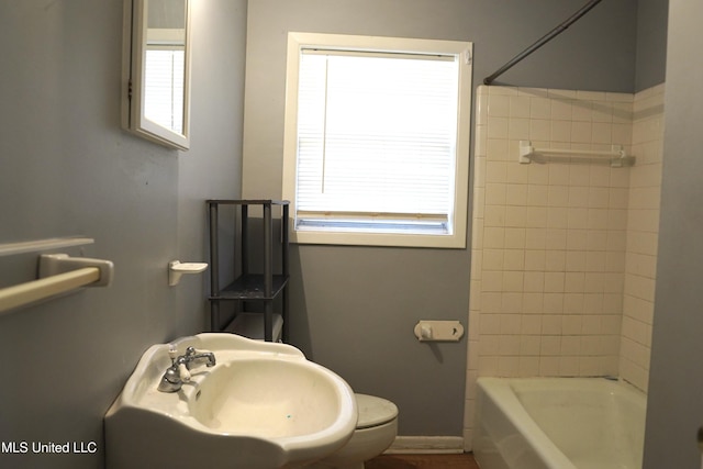 full bathroom with tiled shower / bath combo, sink, and toilet