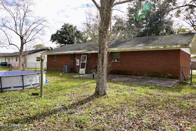 rear view of property featuring a yard and central air condition unit