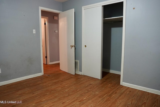 unfurnished bedroom featuring hardwood / wood-style floors and a closet