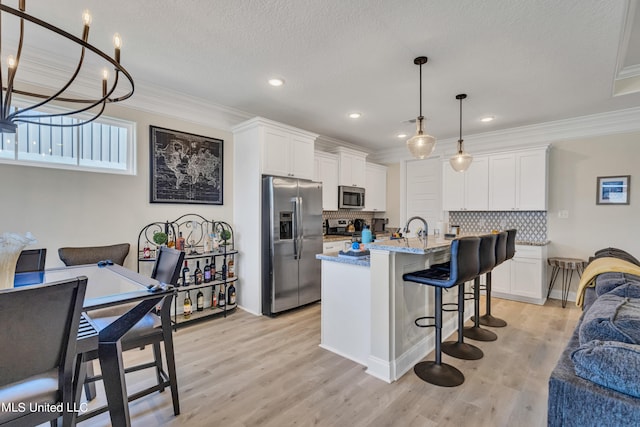 kitchen with decorative backsplash, a center island with sink, appliances with stainless steel finishes, white cabinetry, and light hardwood / wood-style floors