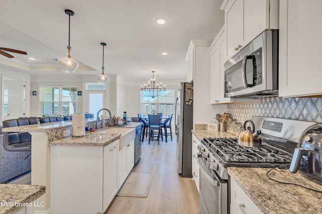 kitchen featuring hanging light fixtures, crown molding, white cabinets, appliances with stainless steel finishes, and light hardwood / wood-style floors