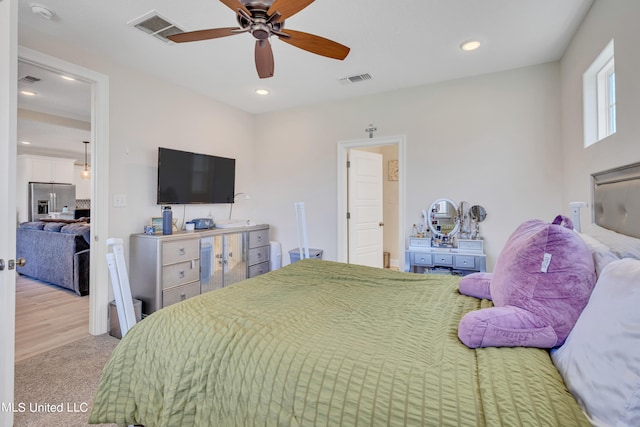 bedroom featuring ceiling fan, light colored carpet, and stainless steel fridge