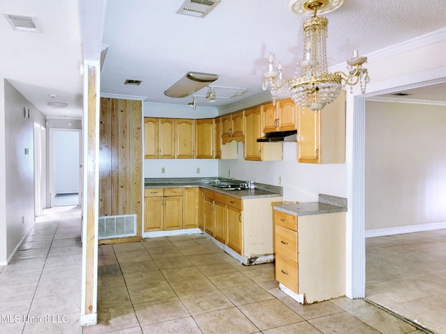 kitchen with hanging light fixtures, ornamental molding, sink, light tile patterned floors, and a textured ceiling