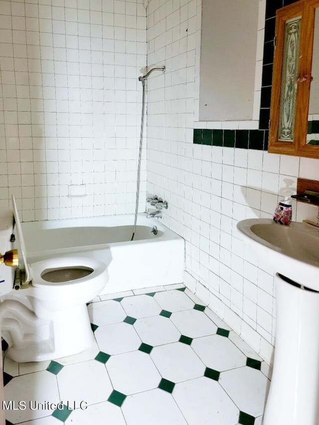 bathroom featuring toilet, tiled shower / bath combo, and tile walls