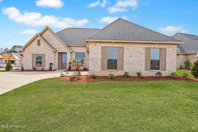 french country inspired facade with a shingled roof, a front lawn, and brick siding