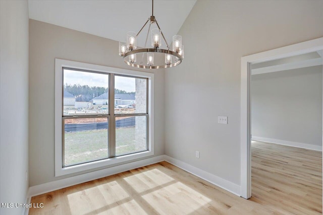 unfurnished dining area with a chandelier, lofted ceiling, and light wood finished floors