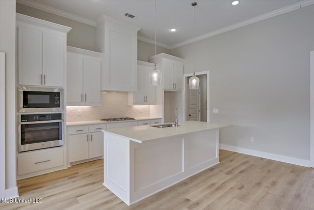 kitchen featuring a center island with sink, built in microwave, gas stovetop, a sink, and stainless steel oven