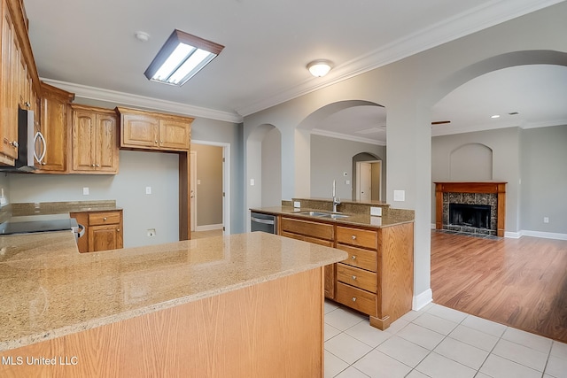 kitchen with sink, light tile patterned floors, kitchen peninsula, stainless steel appliances, and crown molding