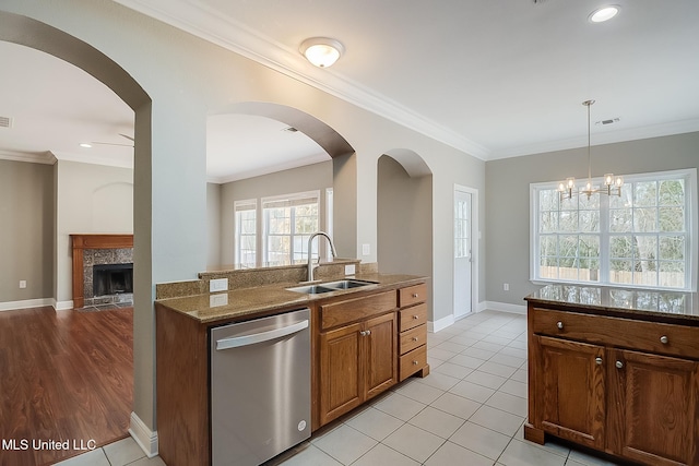 kitchen with stone counters, dishwasher, sink, hanging light fixtures, and ornamental molding