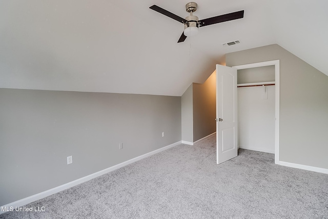 unfurnished bedroom with ceiling fan, a closet, lofted ceiling, and light carpet