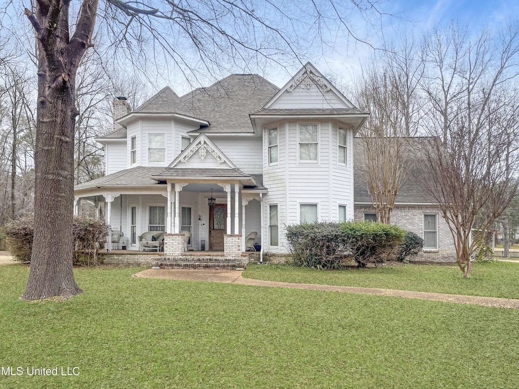 victorian house featuring covered porch and a front yard