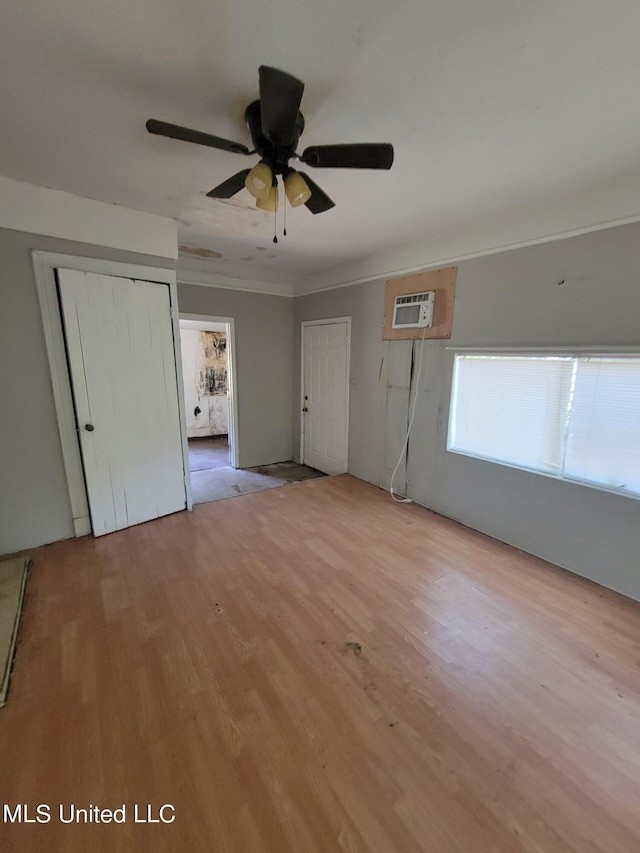 unfurnished bedroom featuring ornamental molding, a wall unit AC, a closet, and light wood finished floors