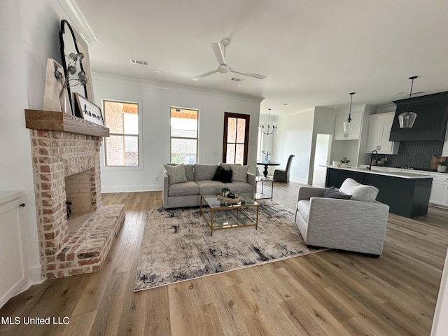 living room featuring ornamental molding, a fireplace, and light hardwood / wood-style floors