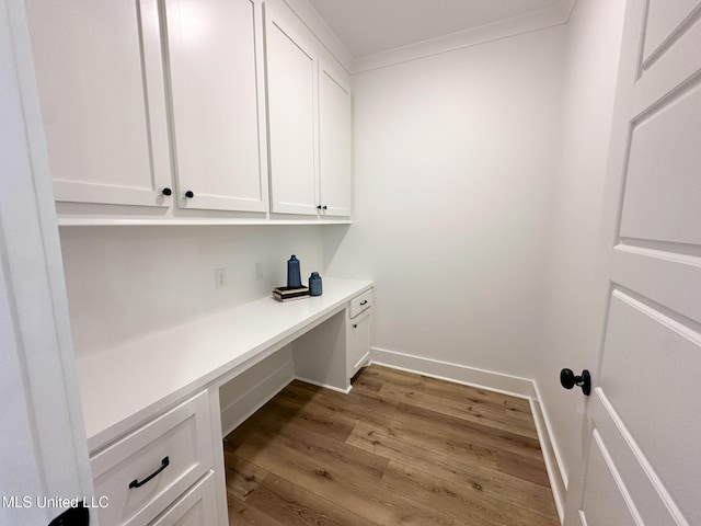 clothes washing area with wood-type flooring and crown molding