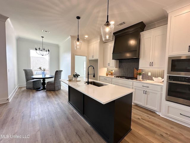 kitchen featuring white cabinetry, sink, oven, hanging light fixtures, and custom exhaust hood