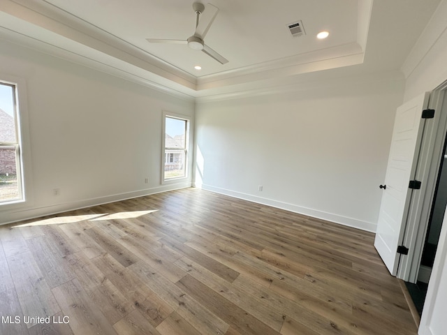 empty room featuring hardwood / wood-style floors, ornamental molding, a raised ceiling, and ceiling fan