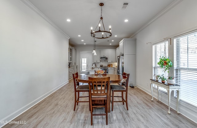 dining room featuring sink, a notable chandelier, light hardwood / wood-style flooring, and ornamental molding