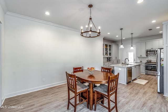 dining area with crown molding, sink, a notable chandelier, and light hardwood / wood-style flooring