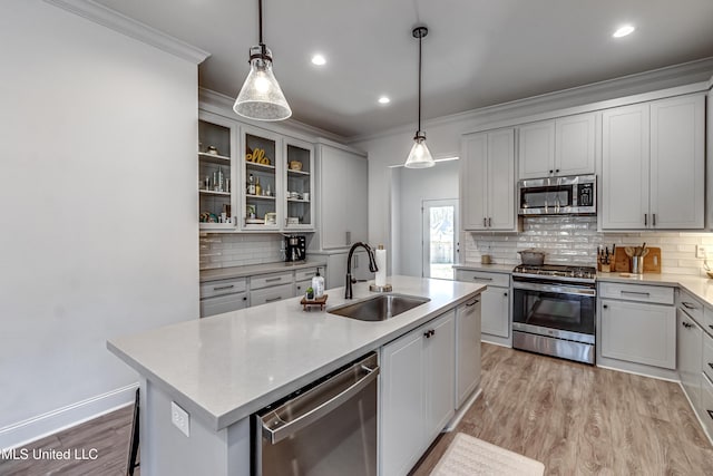 kitchen featuring sink, backsplash, hanging light fixtures, stainless steel appliances, and a center island with sink