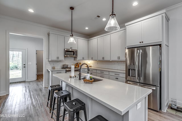 kitchen with appliances with stainless steel finishes, sink, white cabinets, and decorative light fixtures