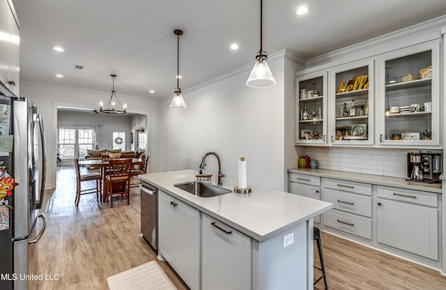 kitchen with hanging light fixtures, an island with sink, appliances with stainless steel finishes, and sink