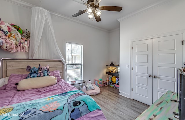 bedroom featuring crown molding, a closet, ceiling fan, and light wood-type flooring