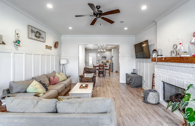 living room with ceiling fan, ornamental molding, a fireplace, and light hardwood / wood-style floors