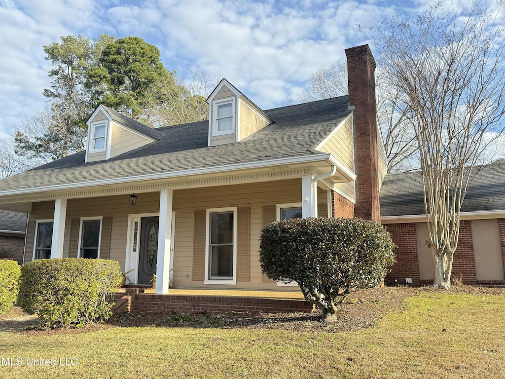 cape cod home featuring covered porch and a front lawn