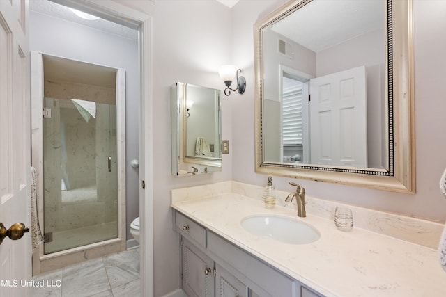 bathroom featuring toilet, vanity, and a shower with shower door