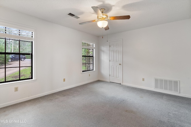 carpeted empty room featuring ceiling fan, a textured ceiling, and a wealth of natural light