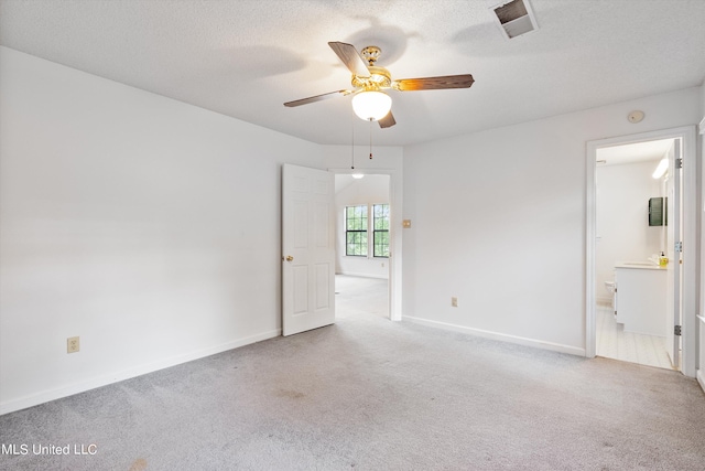 spare room with light carpet, ceiling fan, and a textured ceiling