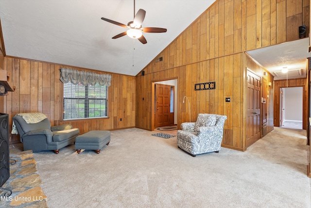 carpeted living room with ceiling fan, high vaulted ceiling, and wooden walls