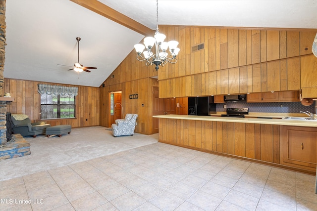 kitchen with sink, hanging light fixtures, beam ceiling, black appliances, and wood walls