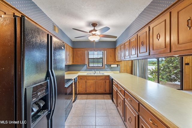 kitchen featuring sink, light tile patterned floors, ceiling fan, black appliances, and a textured ceiling