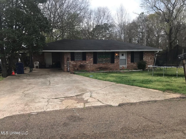 ranch-style home featuring a carport, a trampoline, and a front lawn