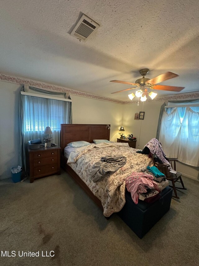 bedroom featuring multiple windows, carpet, visible vents, and a textured ceiling