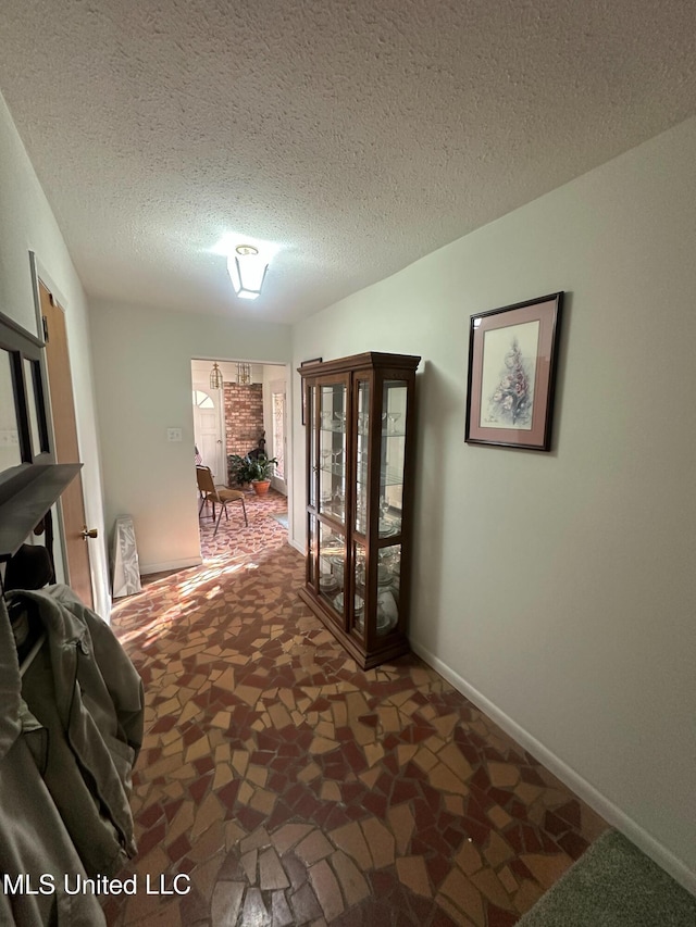 hallway with baseboards and a textured ceiling