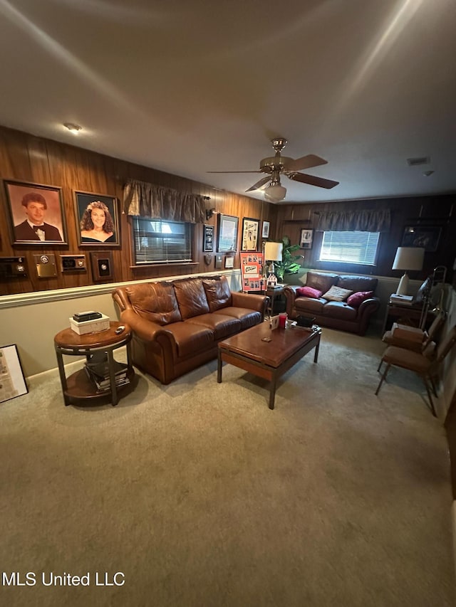 living area featuring carpet flooring, wood walls, and ceiling fan