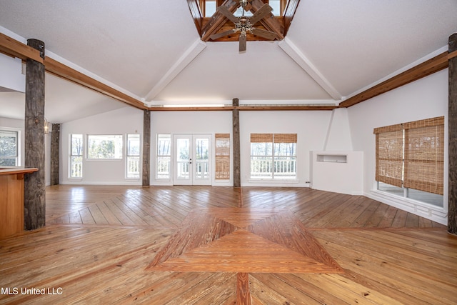 unfurnished living room featuring lofted ceiling with beams, a barn door, and plenty of natural light