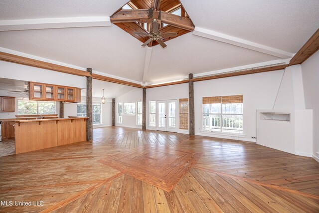 unfurnished living room with a barn door, high vaulted ceiling, and a healthy amount of sunlight